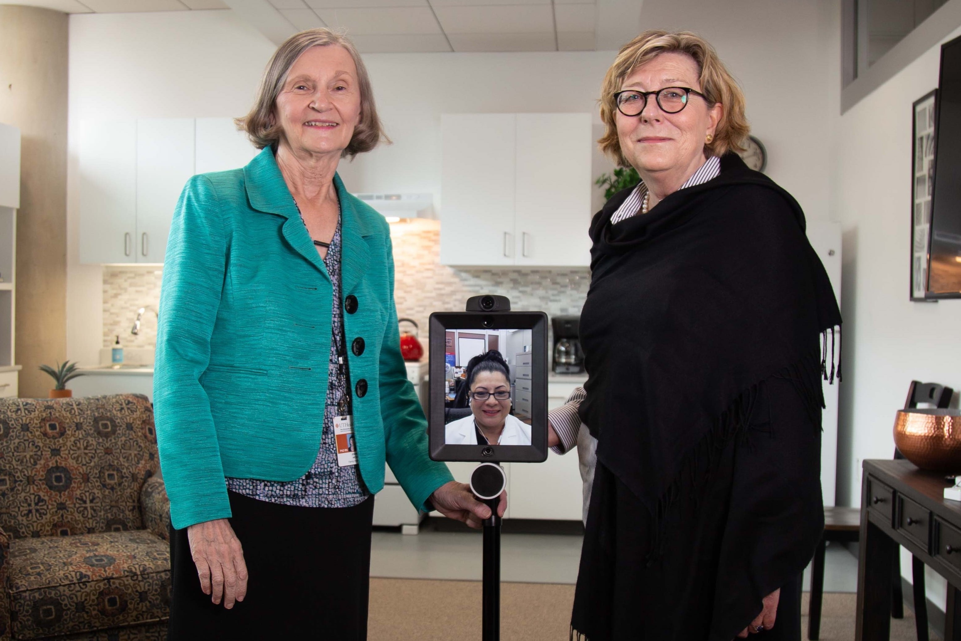 Interior backdrop of CSON Smart apartment with two females standing close to each other and a tablet-mounted Segway virtual unit between them.